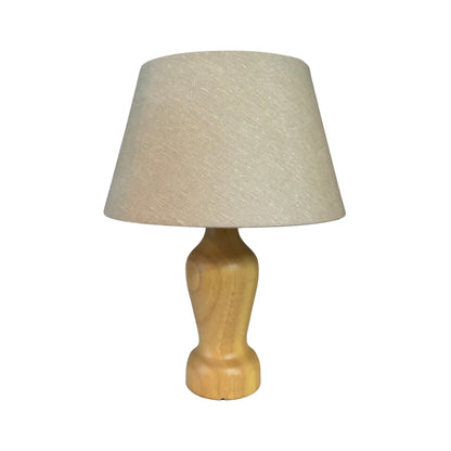 Tafellamp Mona met een lichtgekleurde houten voet en een zandkleurige linnen kap tegen een witte achtergrond.
