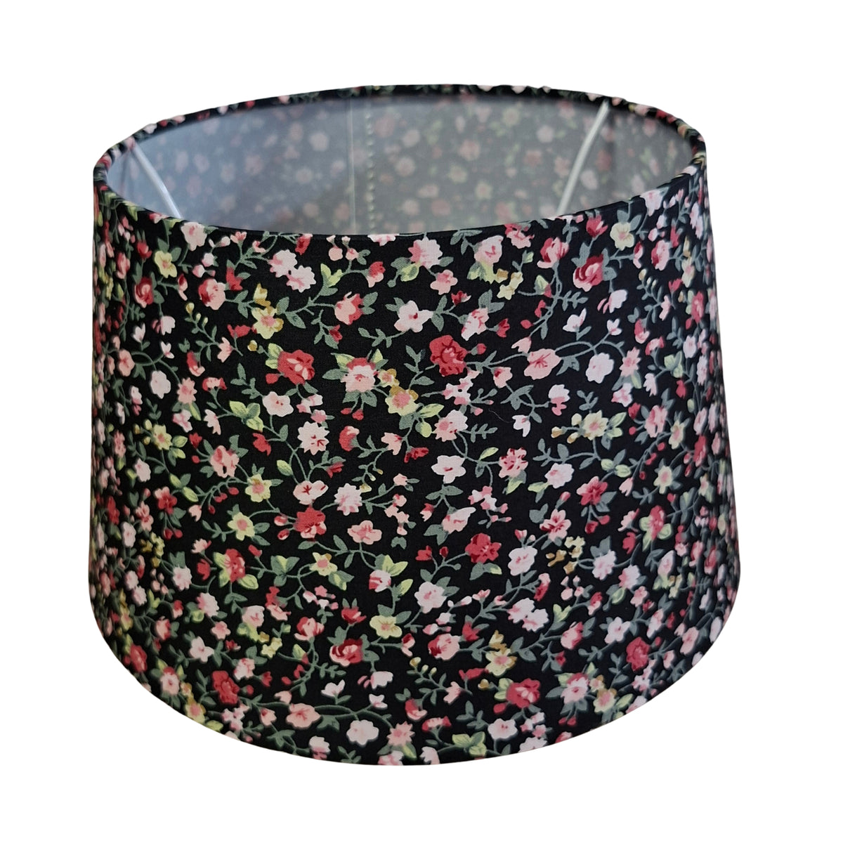 Een zwarte lampenkap met een bloemenprint in chintz, perfect voor een bohemian touch in jouw interieur.